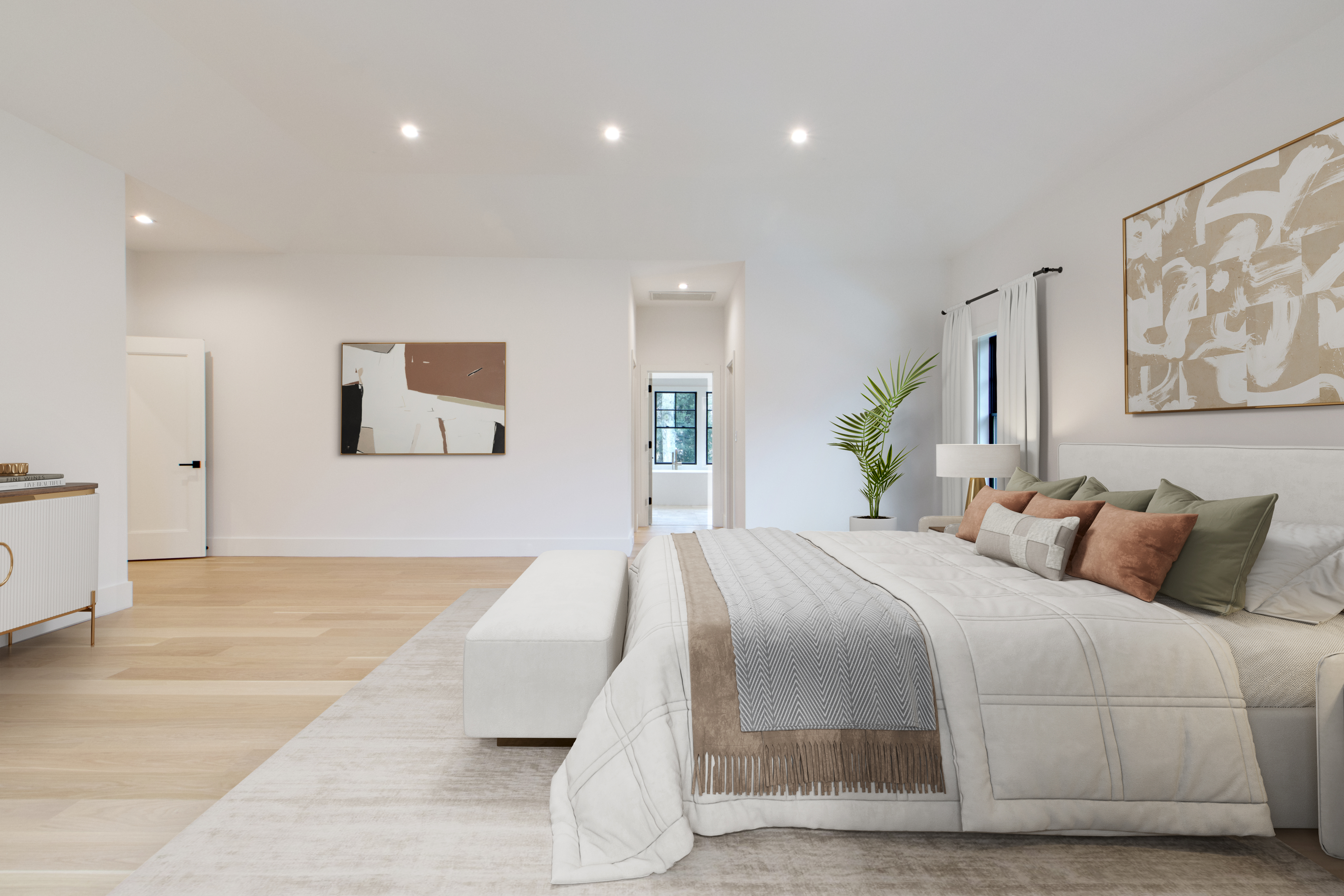 This spacious primary bedroom features a clean, modern aesthetic with light hardwood floors and a neutral color palette. The room is anchored by a plush bed with layered bedding, a minimalist bench, and abstract wall art, all illuminated by recessed lighting. A doorway leads to an adjacent bathroom, creating an open and airy flow throughout the suite.
