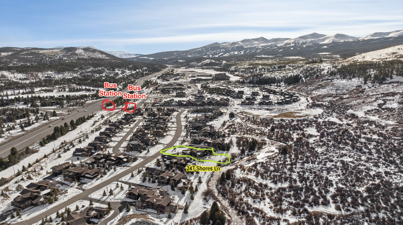 This aerial shot showcases a residential area in a mountain setting during winter. Several houses are visible, nestled amongst snow-covered trees and terrain, with a nearby roadway and a bus stop. The overall impression is a serene and picturesque neighborhood in a mountain resort area.
