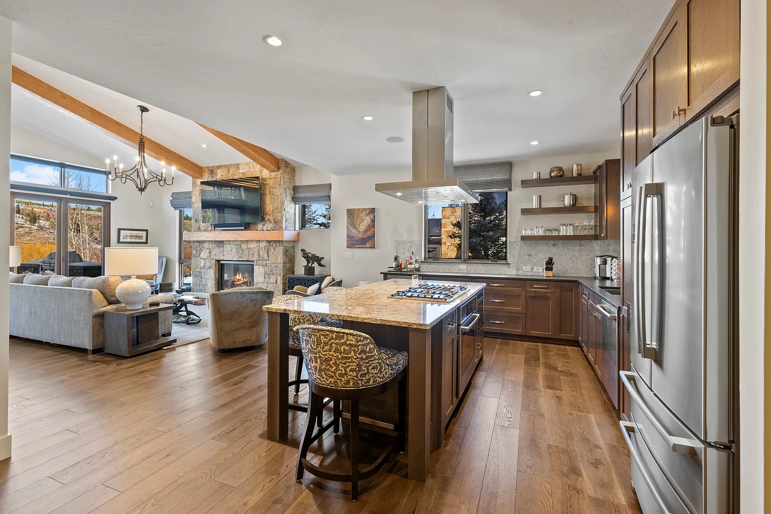 This image showcases a well-appointed kitchen that seamlessly blends with the living space. The kitchen features a central island with a cooktop, stainless steel appliances, and custom cabinetry. The open-concept design enhances the flow and creates an inviting atmosphere, perfect for entertaining.