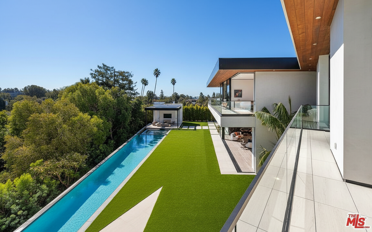 This image showcases the exterior of a modern home, highlighting its luxurious outdoor amenities. A sleek, elongated pool stretches alongside a well-manicured lawn, with a cabana-like structure at the far end. The property also features a modern architectural design with a balcony and glass railings.