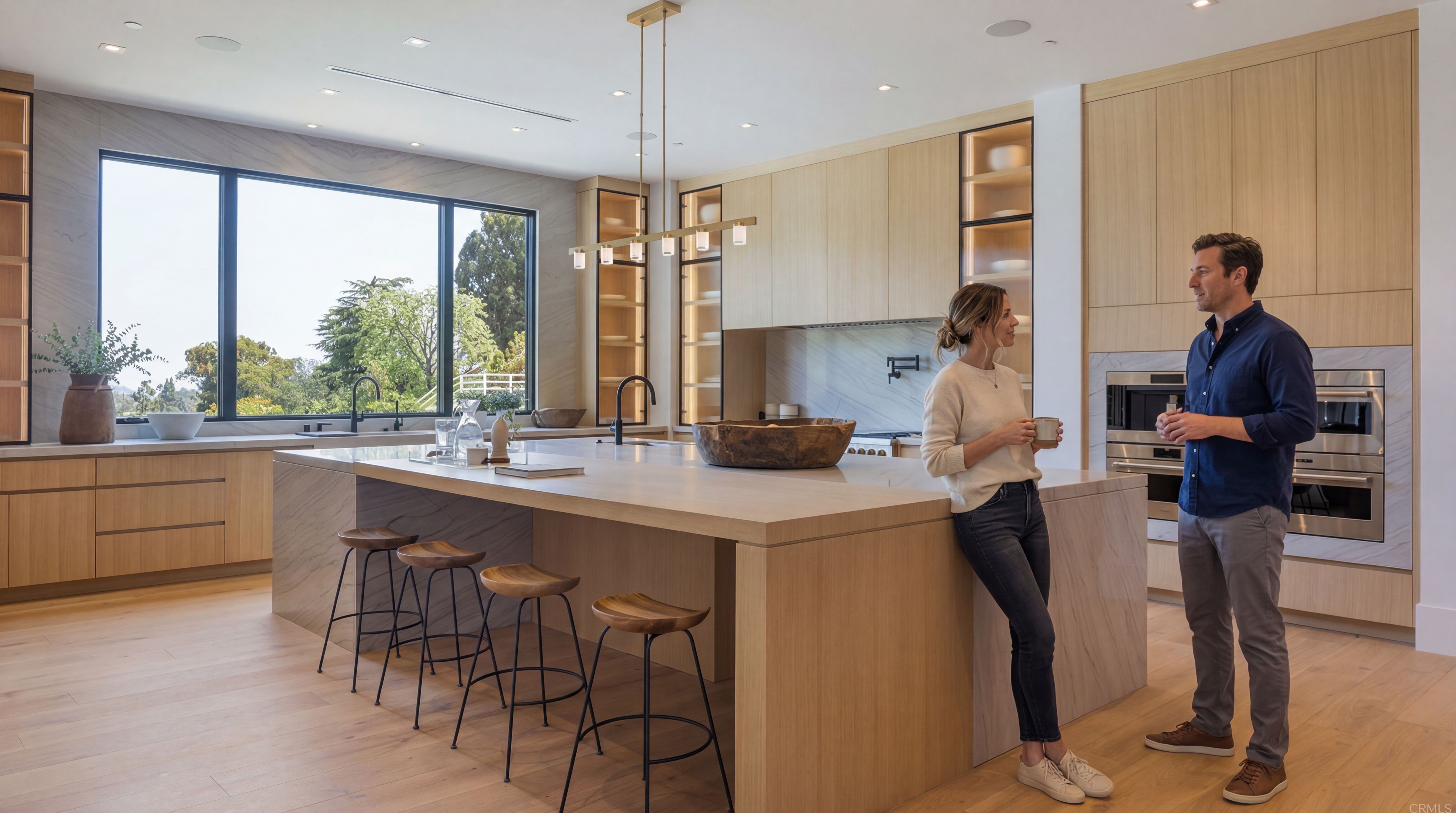 This stunning contemporary kitchen features light wood cabinetry, elegant marble-wrapped islands, and premium stainless steel appliances. A large picture window floods the space with natural light while providing a serene outdoor view, complemented by minimalist wooden bar stools and warm, integrated lighting. The open-concept design is highlighted by a sophisticated, neutral color palette that emphasizes clean lines and high-end craftsmanship.