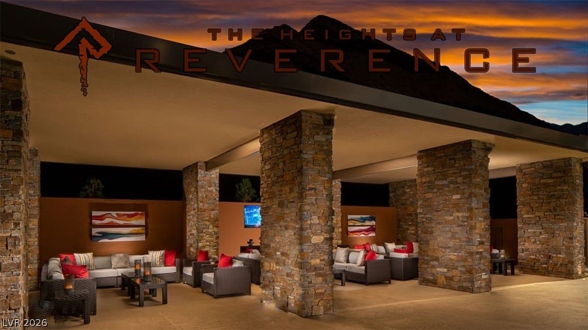 This image showcases an expansive, open-air outdoor lounge area at 'The Heights at Reverence,' featuring high-end modern patio furniture and large stone columns. The space is designed for luxury communal gathering, complete with ambient lighting, wall-mounted television screens, and artistic wall decor. Its covered design and sophisticated, resort-style aesthetic provide a comfortable and inviting atmosphere for social events or leisure.