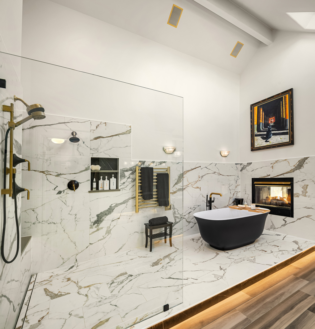 This is a luxurious primary bathroom featuring a glass-enclosed shower with gold fixtures and a rainfall showerhead, a freestanding black bathtub with gold faucet, and a modern fireplace. The walls and floors are covered in marble with gold veining, creating a cohesive and elegant design. The room is well-lit with recessed lighting and sconces, enhancing the spa-like atmosphere.