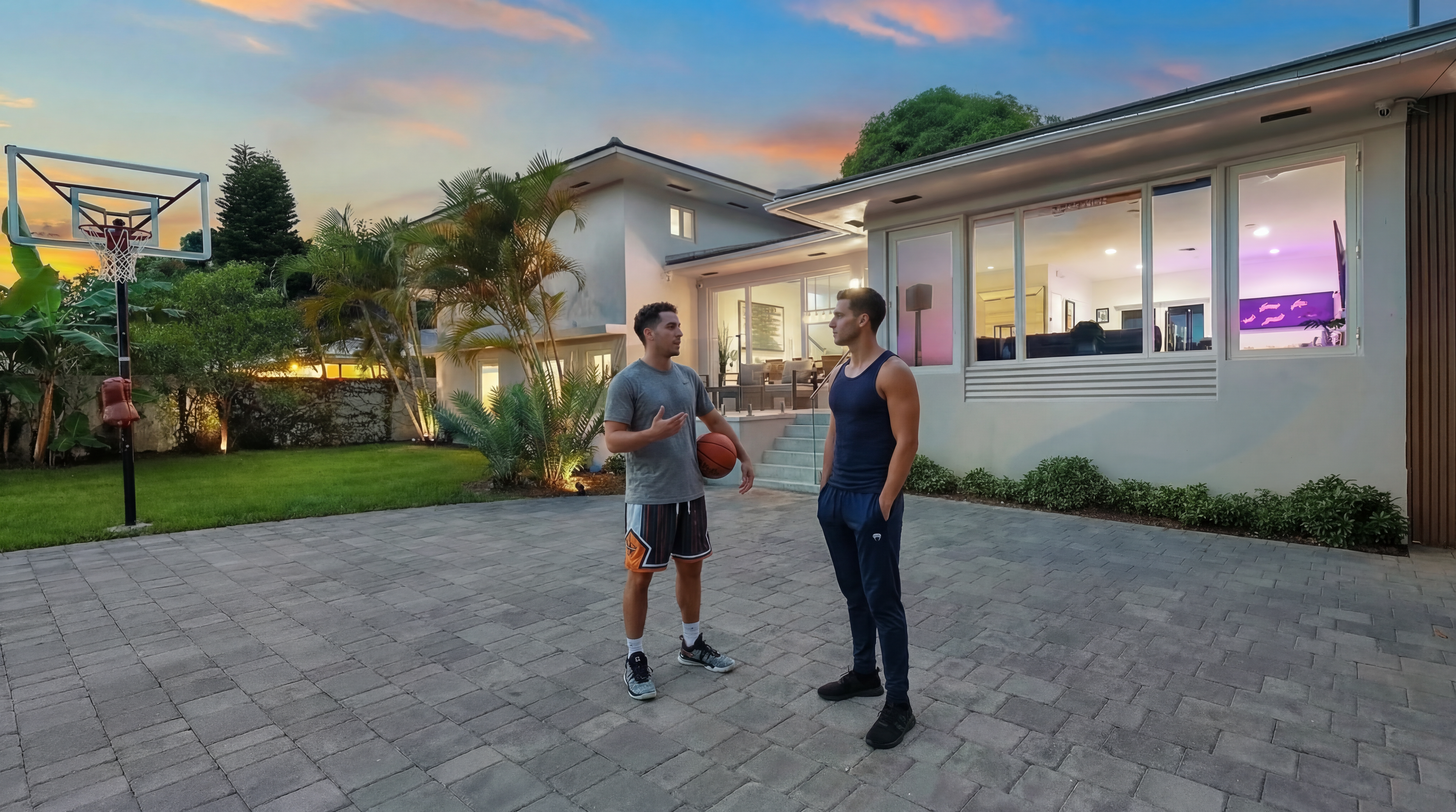 This image features a well-maintained yard and driveway in front of a modern home. Two men are seen conversing near a basketball hoop, adding a sense of activity and potential for recreation. The meticulously paved driveway and manicured lawn enhance the property's curb appeal, suggesting a residence that is both stylish and functional.
