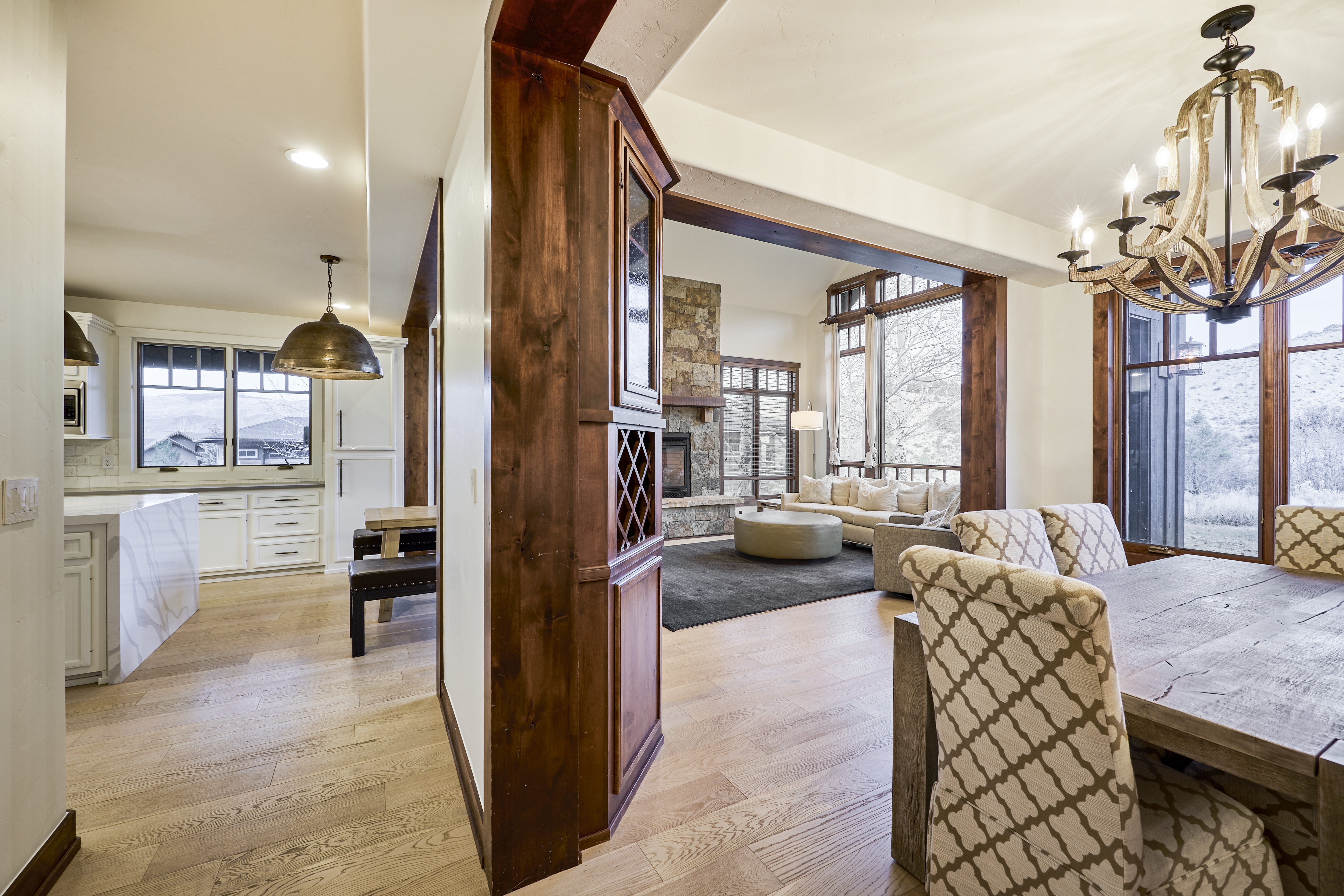 This interior shot showcases a dining area seamlessly connected to the kitchen and living room. The dining room features a rustic wooden table and patterned chairs, illuminated by an ornate chandelier. The open-concept design creates an inviting space for entertaining and family gatherings.