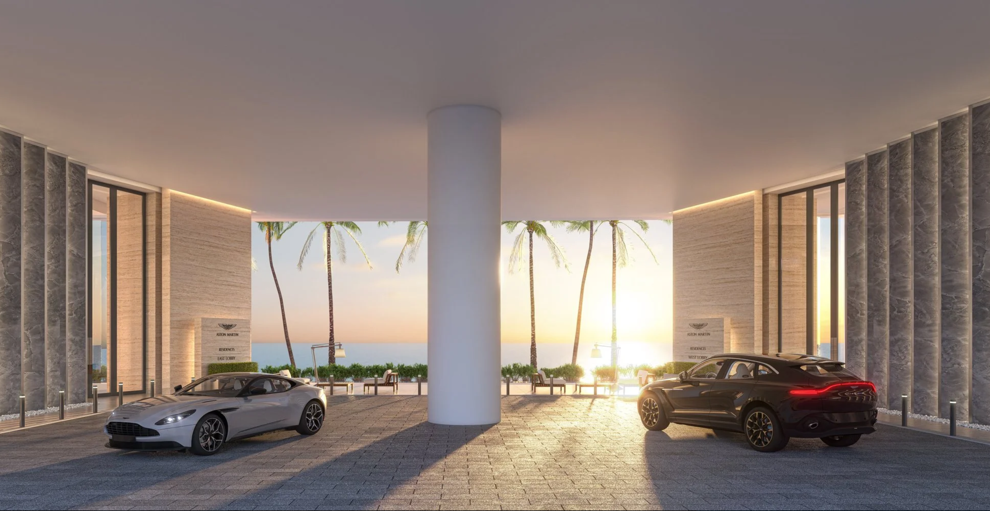 This image showcases the grand entryway of a luxurious residence. Two high-end vehicles, a silver coupe and a dark SUV, are parked under a covered area supported by a large white pillar. The backdrop features swaying palm trees, a glimpse of the ocean, and the warm light of the sun, creating an inviting and upscale arrival experience.