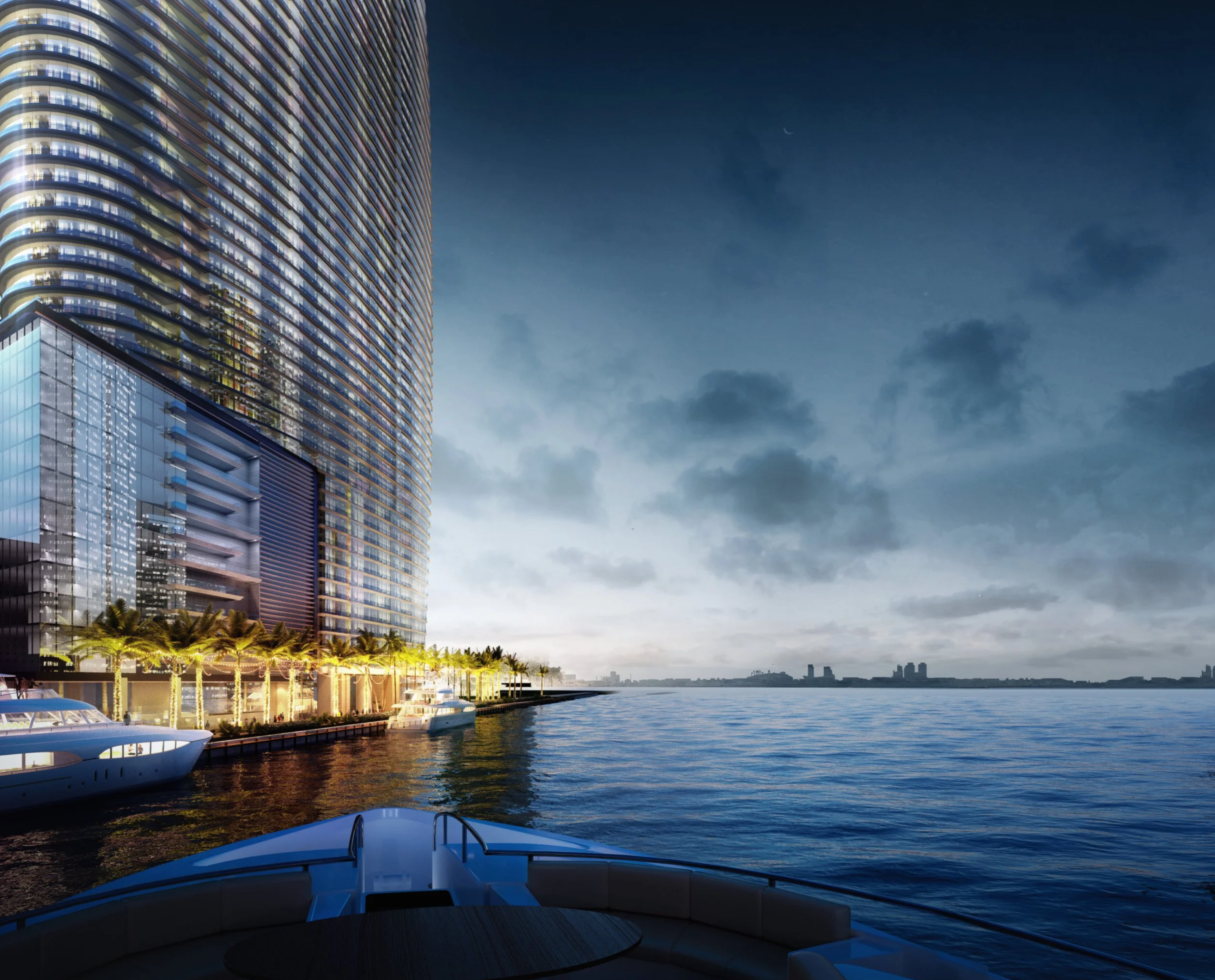 This image showcases the side view of a modern luxury building situated along the waterfront, likely a high-end condominium or apartment complex. The building features extensive glass facades and private balconies. Several yachts are docked nearby, suggesting a privileged lifestyle and prime real estate location.