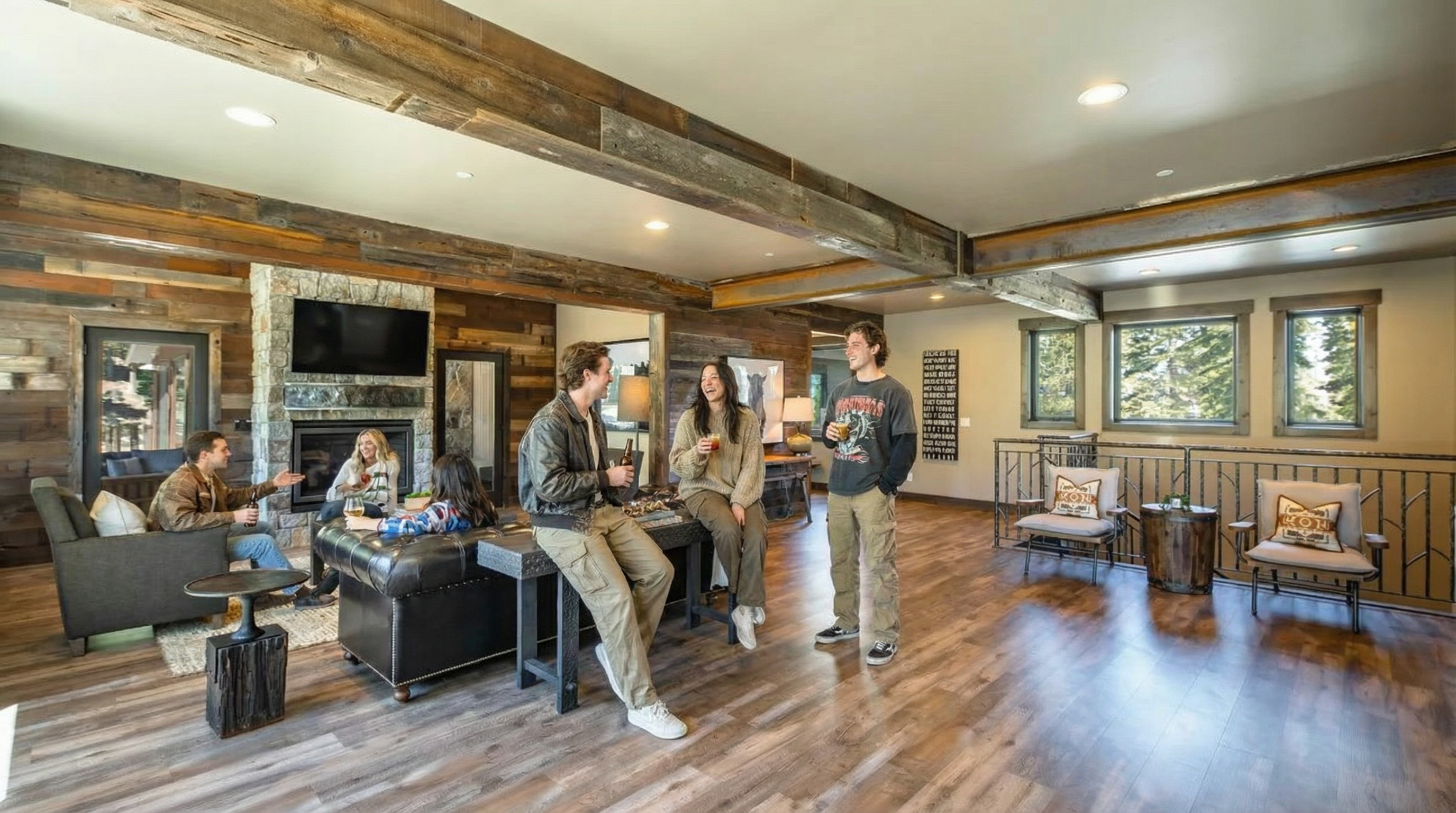 This is a living room featuring rustic elements such as wooden beams and wall cladding paired with modern furniture. People are gathered, creating a welcoming and lived-in atmosphere. The room boasts a stone fireplace and windows that provide natural light, adding to the appeal of this comfortable and inviting space.