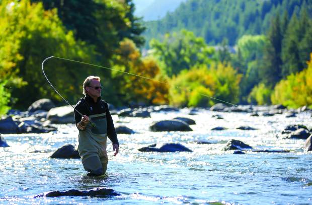 This image features a man fly fishing in a river. The surrounding landscape showcases lush greenery and trees, suggesting a natural and scenic environment. The scene evokes a sense of recreation and outdoor lifestyle, potentially highlighting nearby natural amenities.