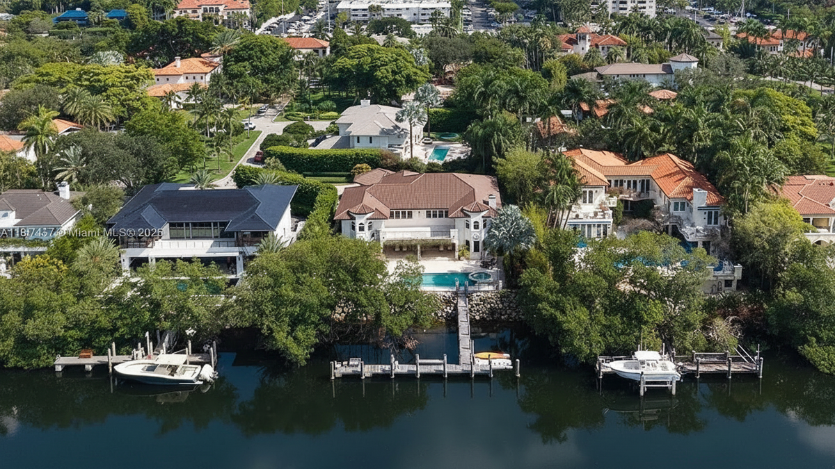 This aerial view showcases several waterfront properties, emphasizing their luxurious appeal. Each home features distinct architectural styles, with some boasting pools and private docks. Lush greenery surrounds the properties, providing privacy and enhancing the overall aesthetic of this exclusive residential area.