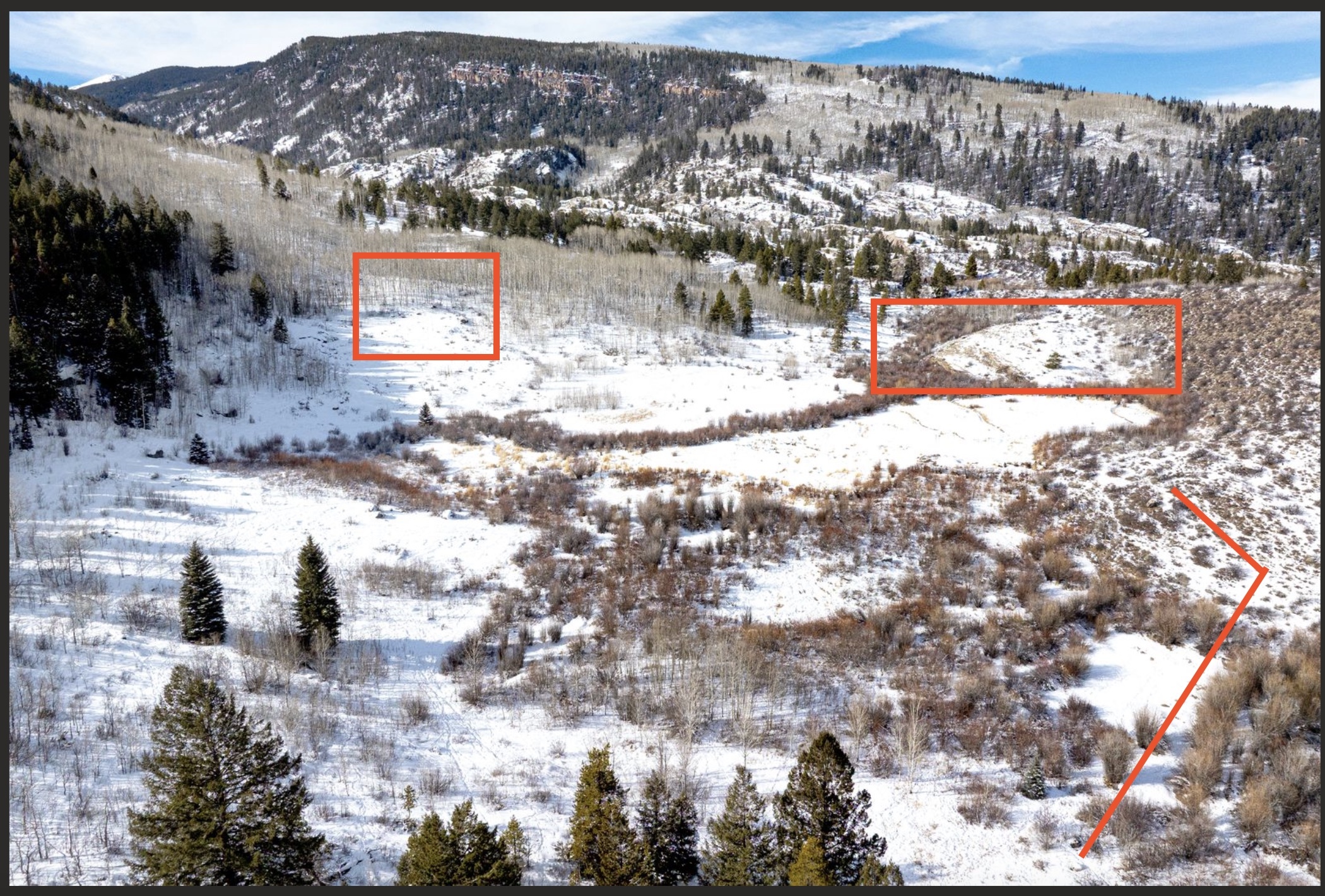 This aerial view showcases a vast, snow-covered landscape, likely a mountain property ideal for buyers who appreciate winter scenery and outdoor activities. Patches of evergreen and aspen trees dot the mountainside, suggesting diverse ecological zones. The landscape offers a sense of seclusion and natural beauty, adding to the property's appeal.