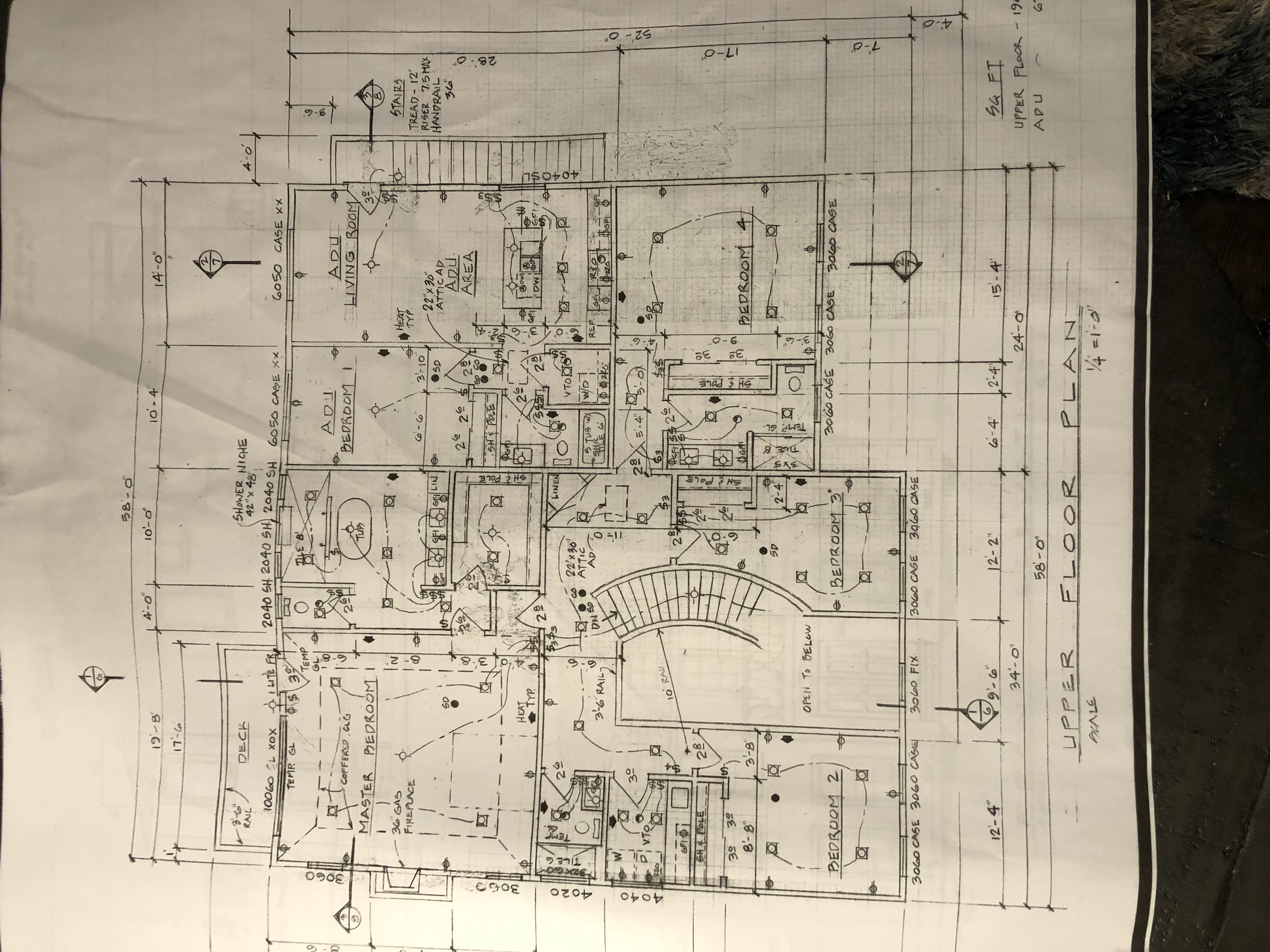 This image is a detailed architectural floor plan blueprint of an upper level featuring a residential layout. It illustrates multiple bedrooms, bathrooms, bathrooms, an ADU (Accessory Dwelling Unit), and a curved staircase overlooking an open-to-below area. The document includes precise measurements, structural notes, and electrical schematics, providing a clear overview of the home's spatial design.