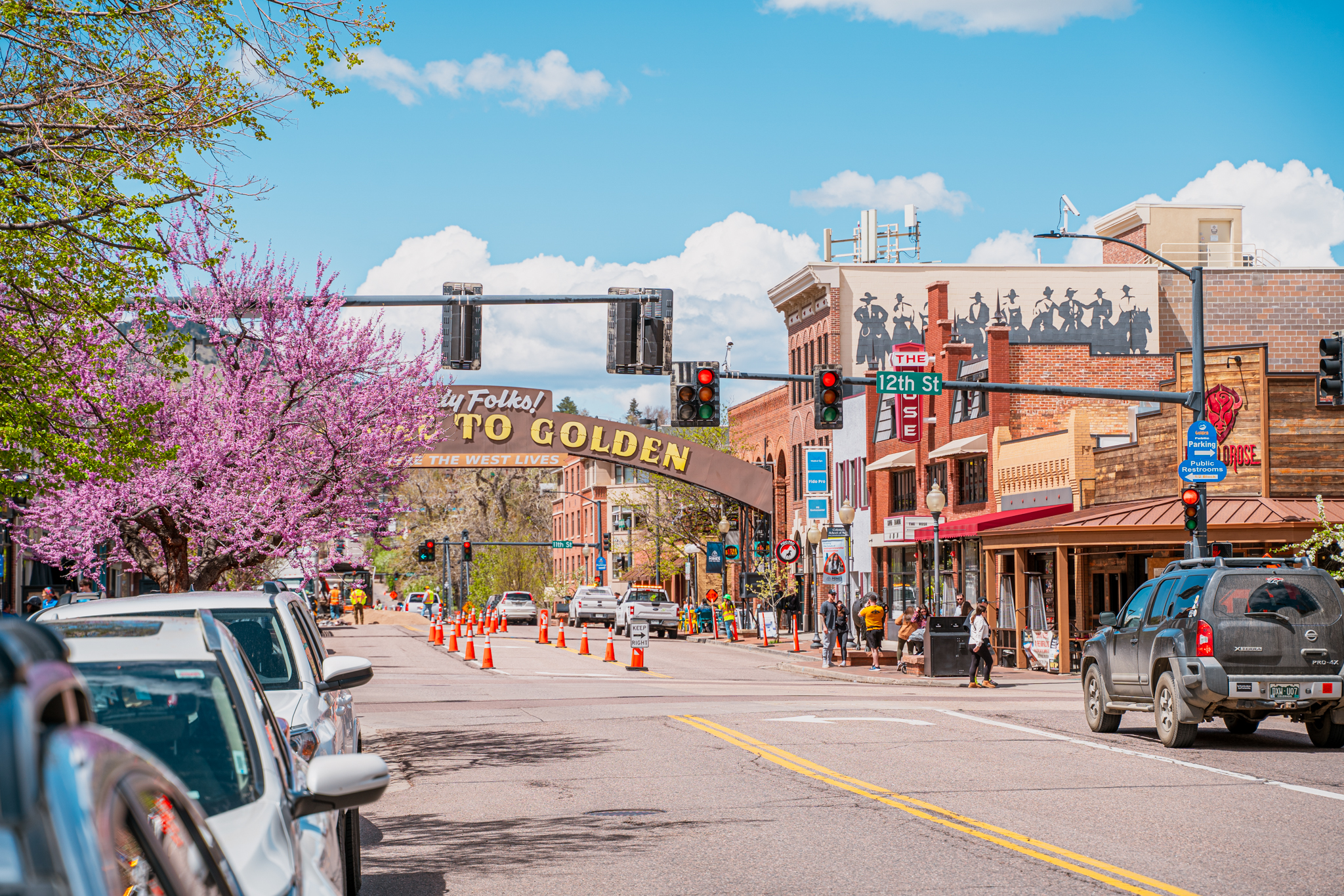 This vibrant street scene prominently features the 'Welcome to Golden' archway. The well-maintained street with mature trees and beautiful foliage suggests a welcoming and established community. With storefronts and visible parking details, this captures the appeal of the location.