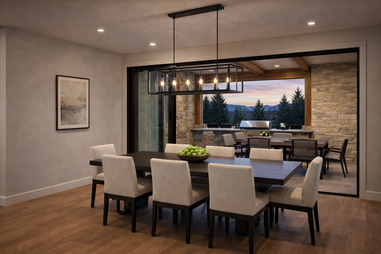 This image showcases an elegant dining room with a long, dark wood table and comfortable, upholstered chairs. A modern, linear chandelier hangs above the table, providing ample lighting. The room opens onto an outdoor patio area with mountain views, enhancing the dining experience with a connection to nature.