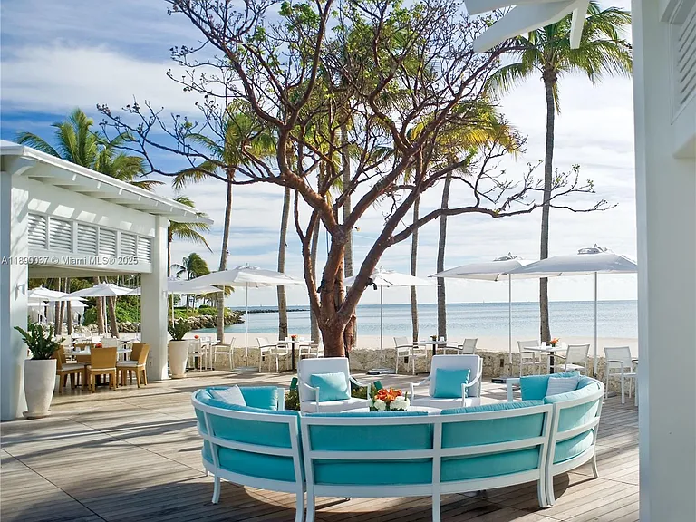 This image showcases a luxurious patio or deck area, likely belonging to a high-end property. It features comfortable, modern outdoor furniture with turquoise accents, inviting guests to relax. The patio offers stunning views of the ocean and manicured landscaping, creating a serene and upscale ambiance.