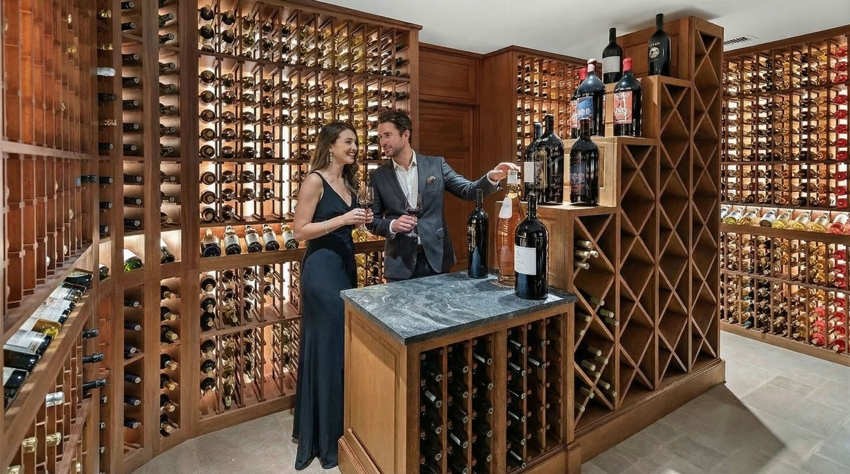 This image showcases a luxurious wine cellar, featuring extensive wooden racking filled with numerous bottles of wine. A couple is seen enjoying a glass of wine, enhancing the ambiance of the space. The room is well-lit, displaying the collection beautifully and adding to the sophisticated appeal of this amenity within the home.