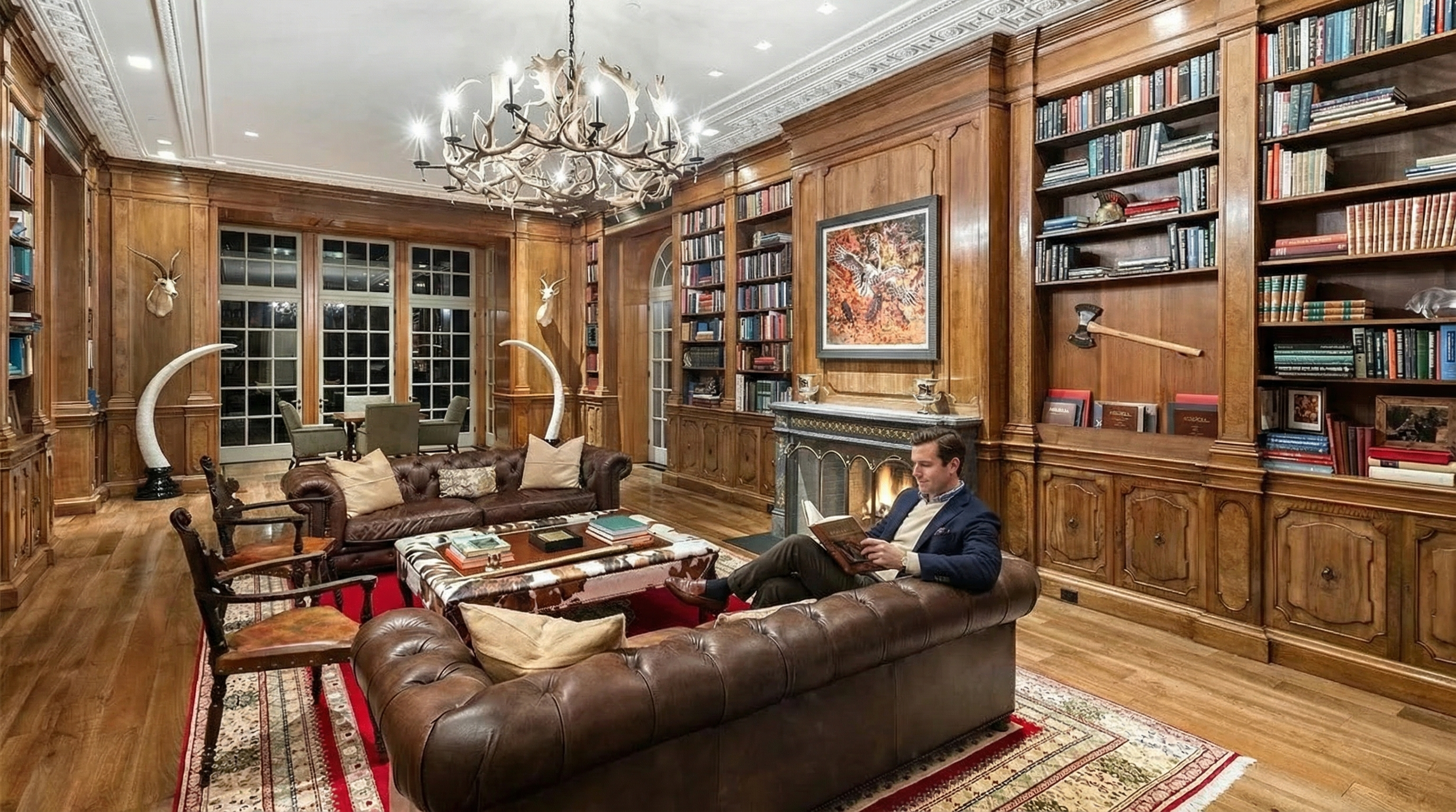 This luxurious home office/study features extensive wood paneling and built-in bookshelves, creating a sophisticated and classic atmosphere. A large leather sofa and ornate rug add to the room's comfort and elegance, while a chandelier provides ample lighting. The fireplace and artwork enhance the room's aesthetic appeal, indicative of a high-end property.