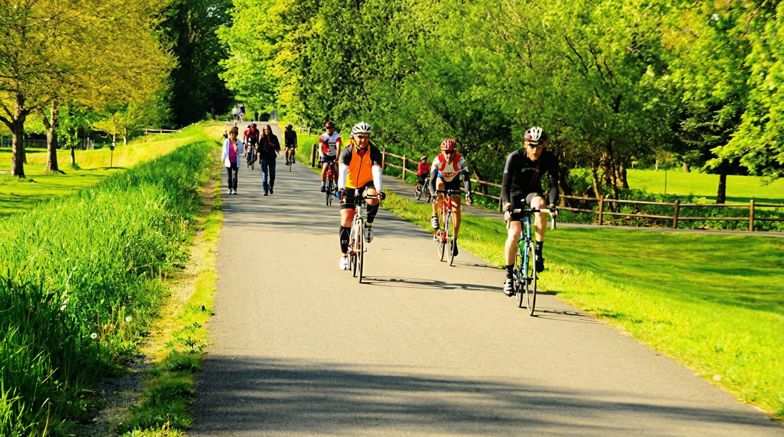 The image showcases a paved path likely part of a park or recreational area, appealing to potential residents seeking an active lifestyle. Cyclists are riding along the path, highlighting its use for outdoor activities. Lush greenery borders the path, providing a scenic and tranquil environment.