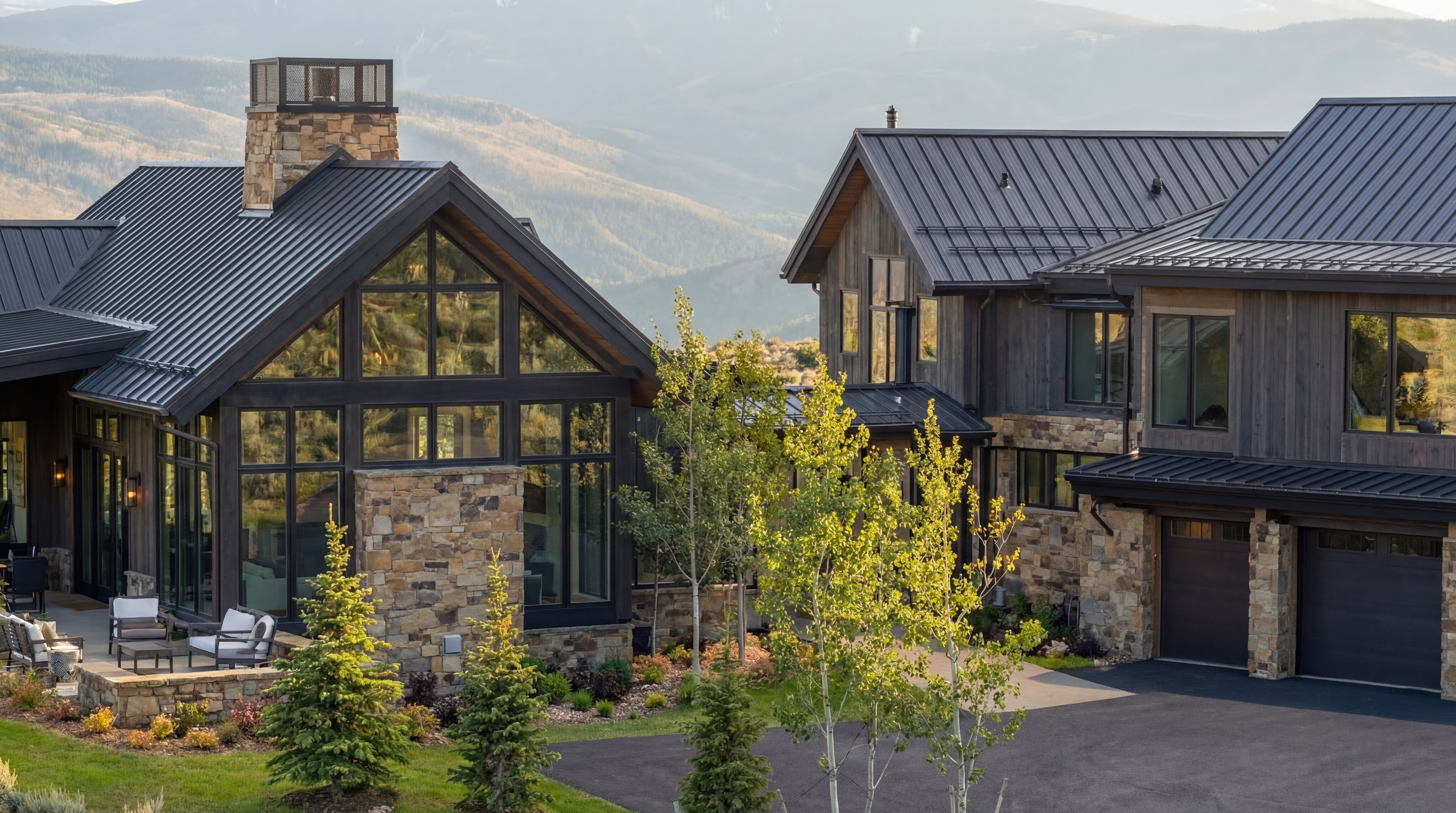 This stunning contemporary mountain estate features a harmonious blend of natural stone and dark-stained vertical wood siding, complemented by sleek black metal roofs. The expansive floor-to-ceiling windows offer panoramic views of the surrounding hills, while the beautifully landscaped exterior and multi-car garage seamlessly integrate with the natural environment. This property exudes a sophisticated, upscale rustic aesthetic perfect for a luxury mountain retreat.
