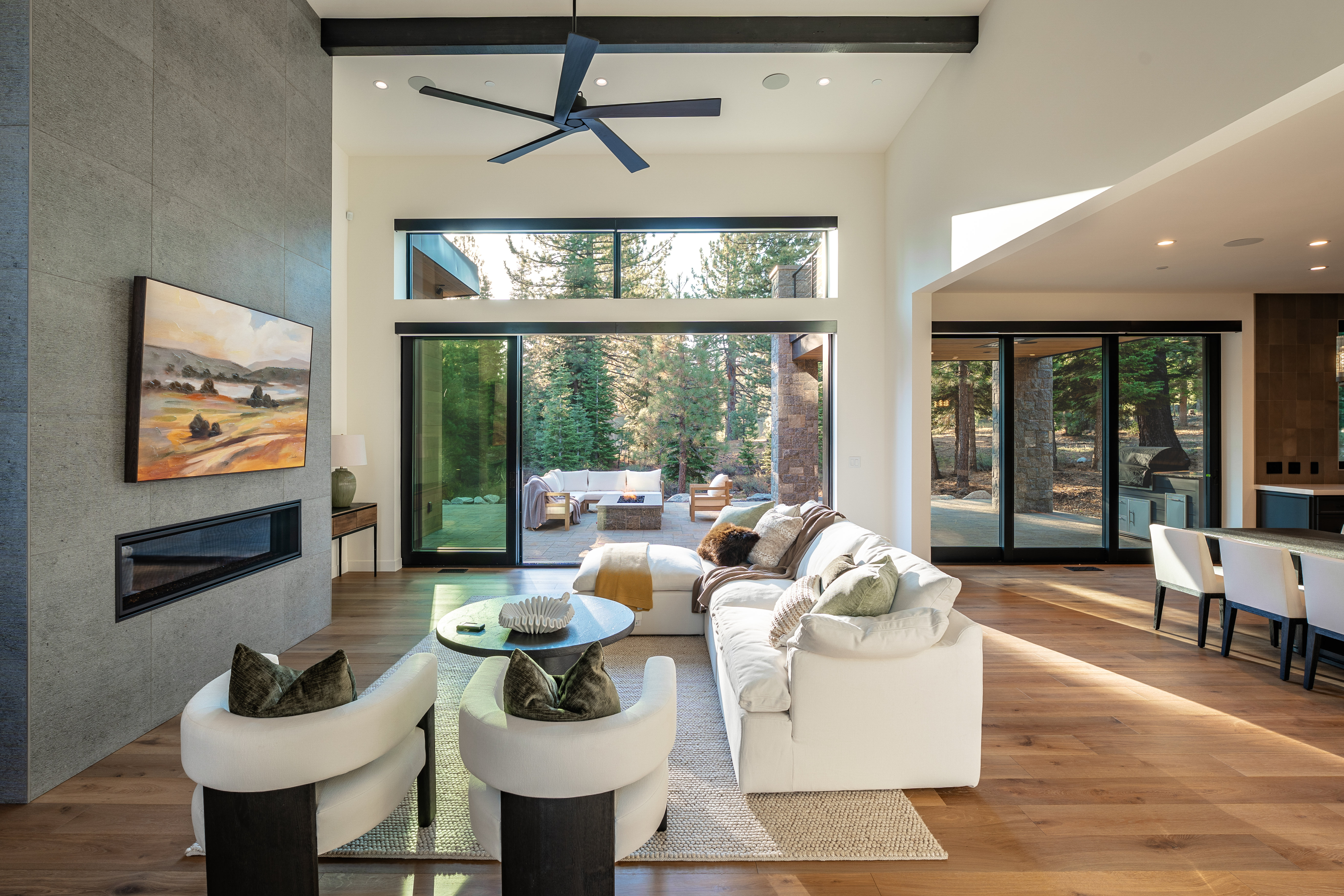 This is a bright and airy living room featuring a modern design with a neutral color palette. The room boasts a large sliding glass door that opens to an outdoor patio, providing ample natural light and a seamless indoor-outdoor transition. Key features include a contemporary fireplace, stylish furniture, and hardwood flooring, creating a sophisticated and inviting atmosphere.