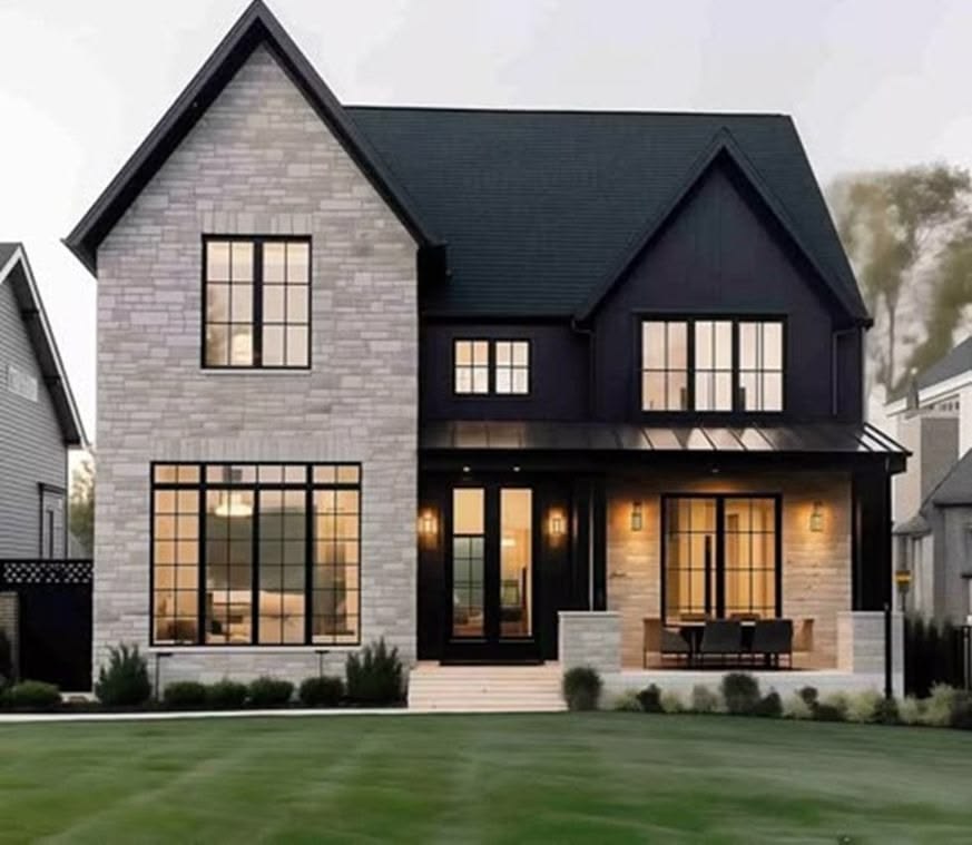 This stunning contemporary two-story home features a striking blend of light stone masonry and bold black siding. The exterior is accented by large, black-framed windows, a welcoming front porch, and a well-manicured lawn, providing excellent curb appeal. The high-contrast design creates a modern farmhouse aesthetic that is both sophisticated and inviting.