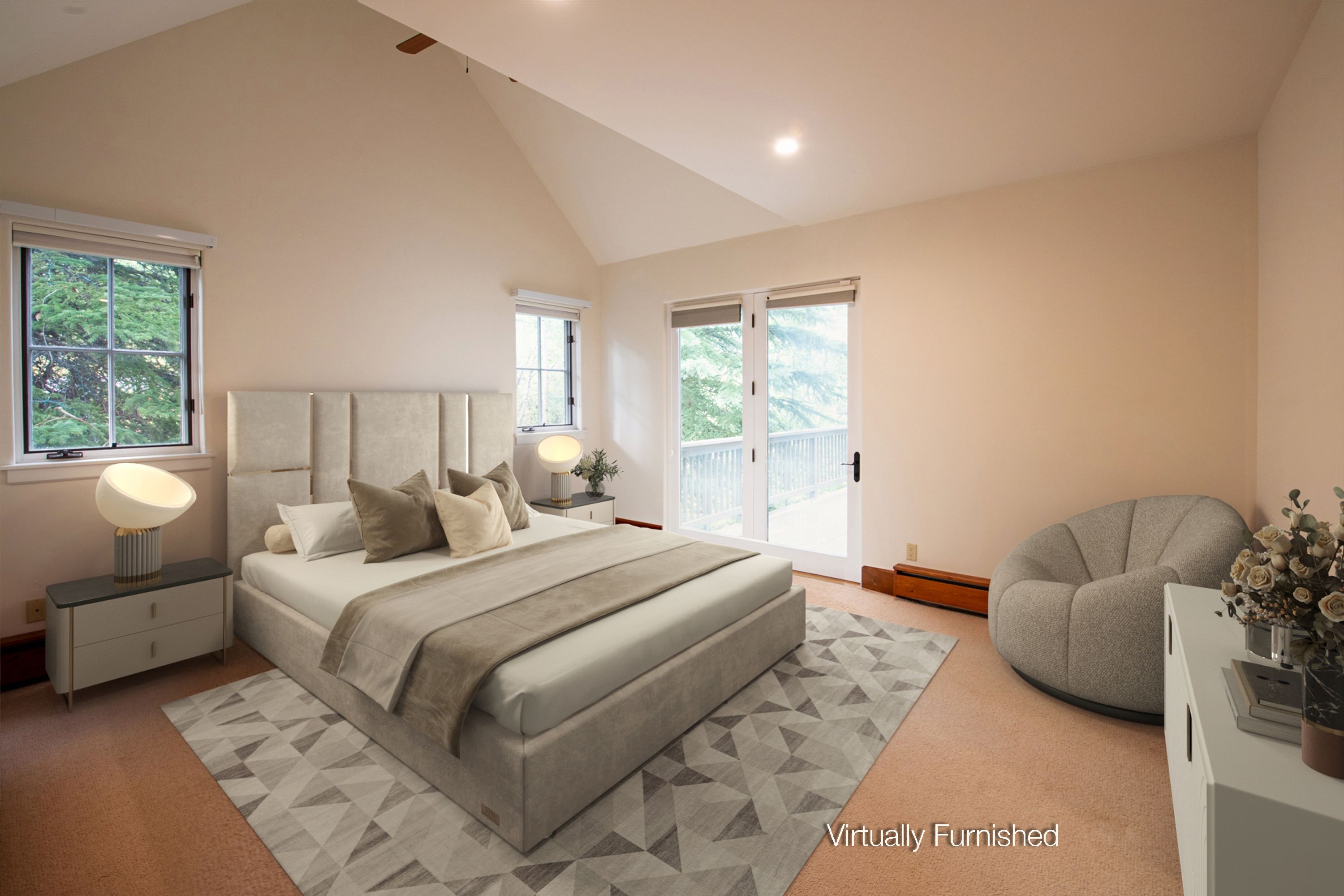 This spacious primary bedroom features a high vaulted ceiling and a neutral color palette, creating a serene and airy atmosphere. The room is anchored by a large, upholstered bed with a geometric-patterned area rug, complemented by a cozy, rounded accent chair and modern bedside lighting. Large windows and a glass door leading to an outdoor deck provide ample natural light and a seamless connection to the surrounding greenery.