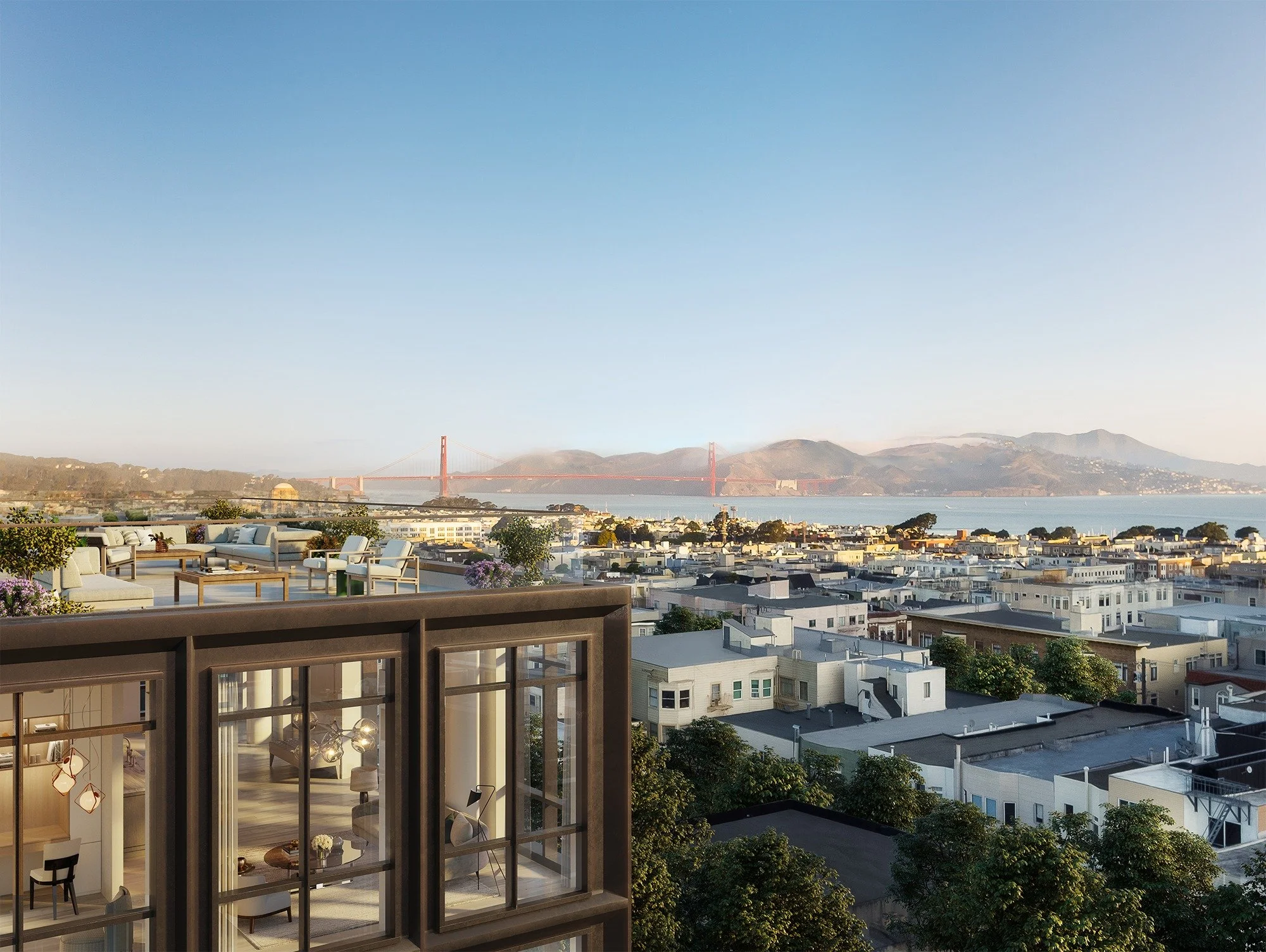 This high-end penthouse terrace offers a stunning, unobstructed panoramic view of the San Francisco skyline and the iconic Golden Gate Bridge. The outdoor space is elegantly furnished with contemporary lounge seating, perfect for entertaining while taking in the sunset. A partial view into the sophisticated interior reveals a modern open-plan living area with premium finishes, highlighting a seamless blend of indoor-outdoor luxury living.