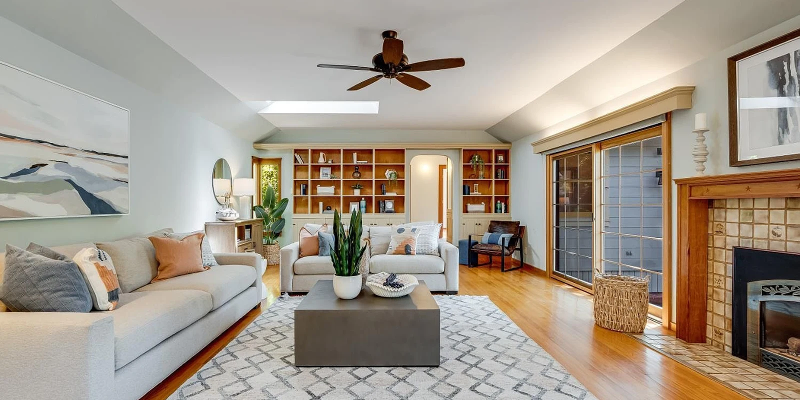 A bright living room with wood floors, a fireplace and built-in shelves